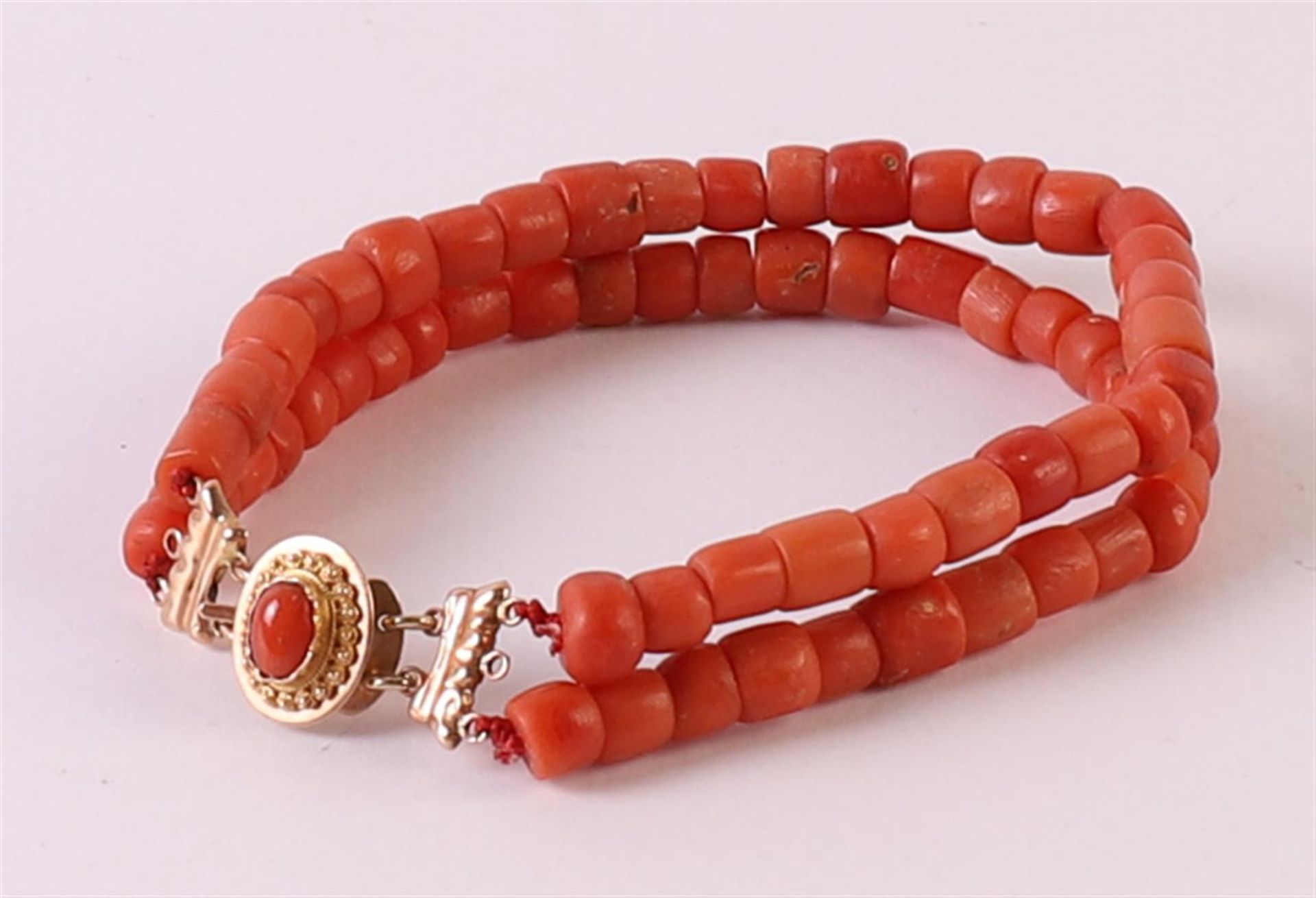A 2-row bracelet of red coral with a 14 kt 585/1000 gold clasp on which a cabochon cut red coral,