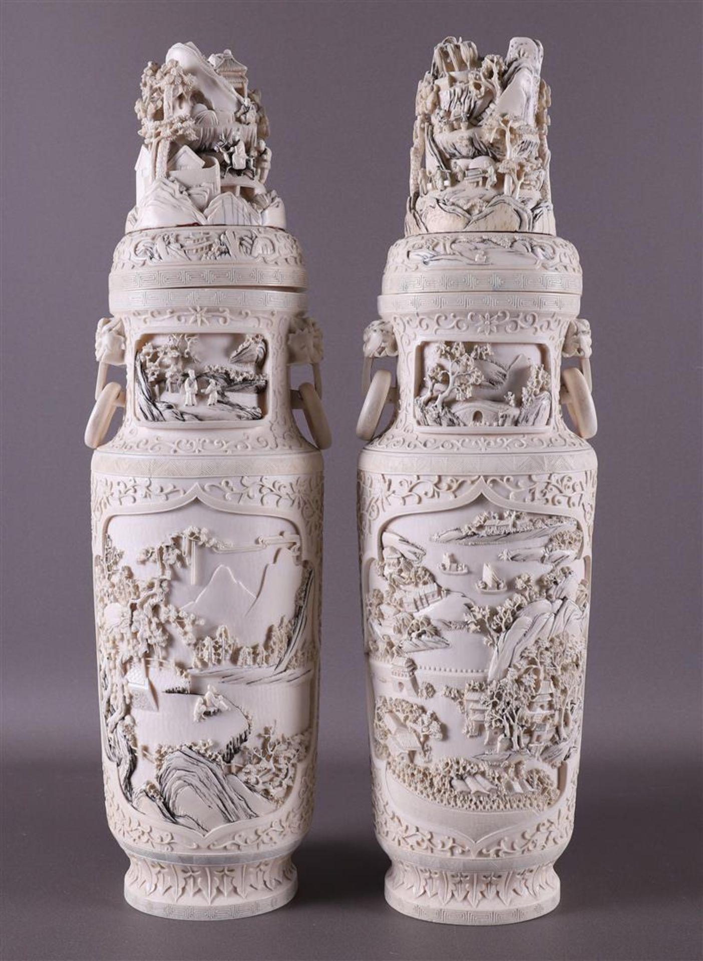 A pair of carved ivory baluster-shaped lidded vases with ringed lion heads as ears, China, Qing