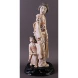 A carved ivory standing okimono with a young girl in her hand, Japan, Meiji (1868-1912), ca. 1890,