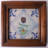 A polychrome earthenware tile depicting a pomegranate, Holland 17th/18th century. In wooden frame, h