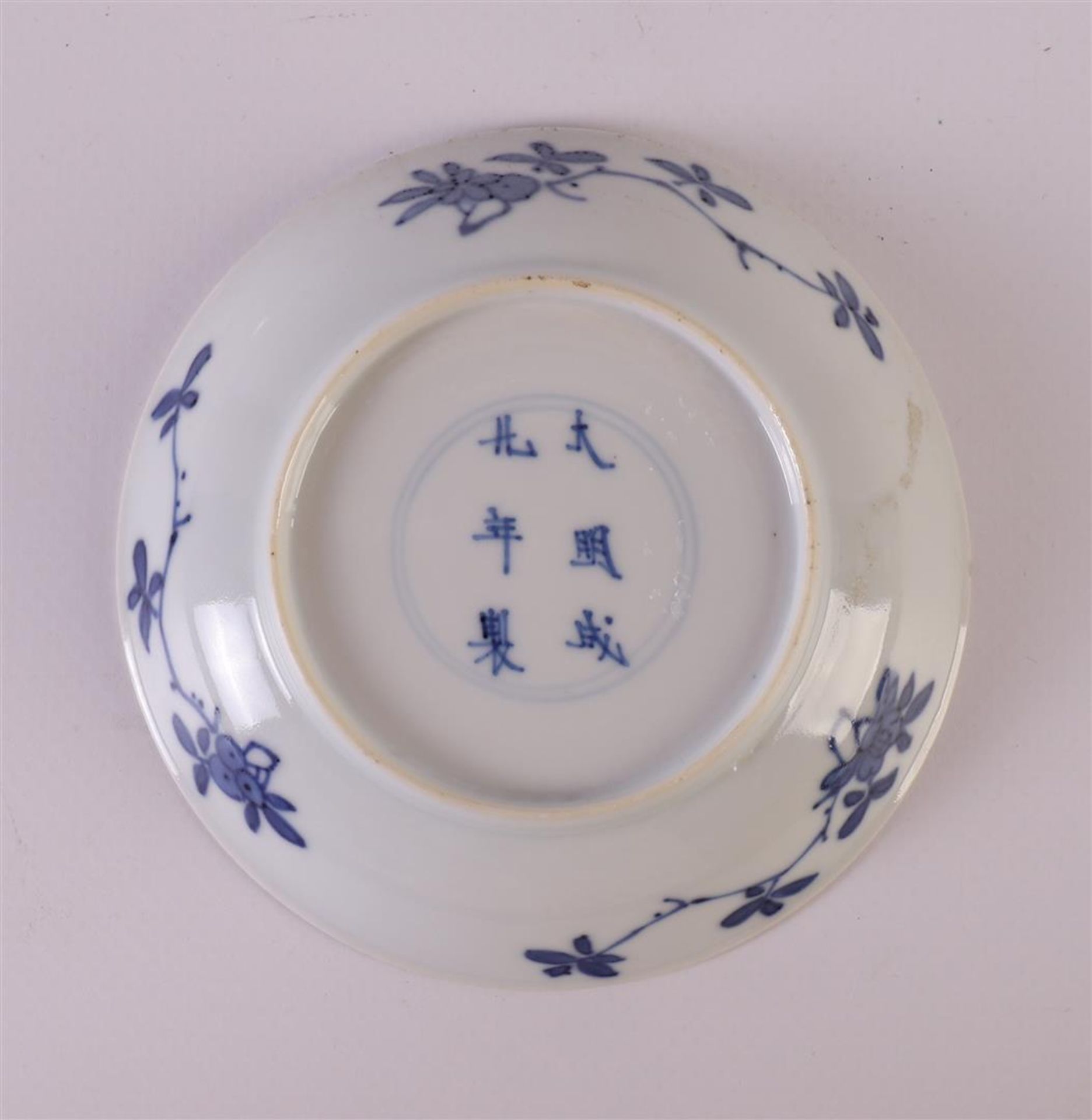 A blue/white porcelain saucer, China, Kangxi, around 1700. Blue underglaze floral decor with - Image 2 of 2