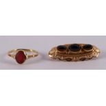 A 14 kt 585/1000 gold contoured brooch, set with three faceted garnets, gross weight 3.4 grams, l