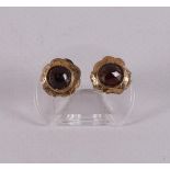 A pair of 14 kt yellow gold stud earrings, set with faceted garnets.