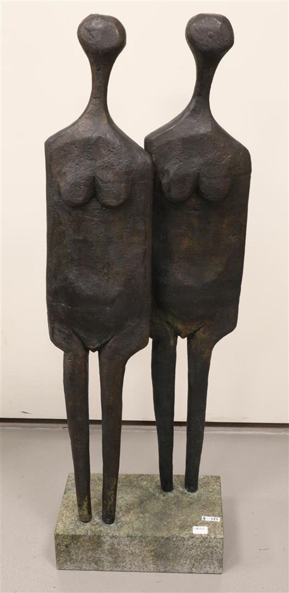 A brown patinated bronze pair of standing figures on a natural stone base.
