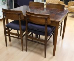 A rectangular vintage dining room table with four matching teak chairs,