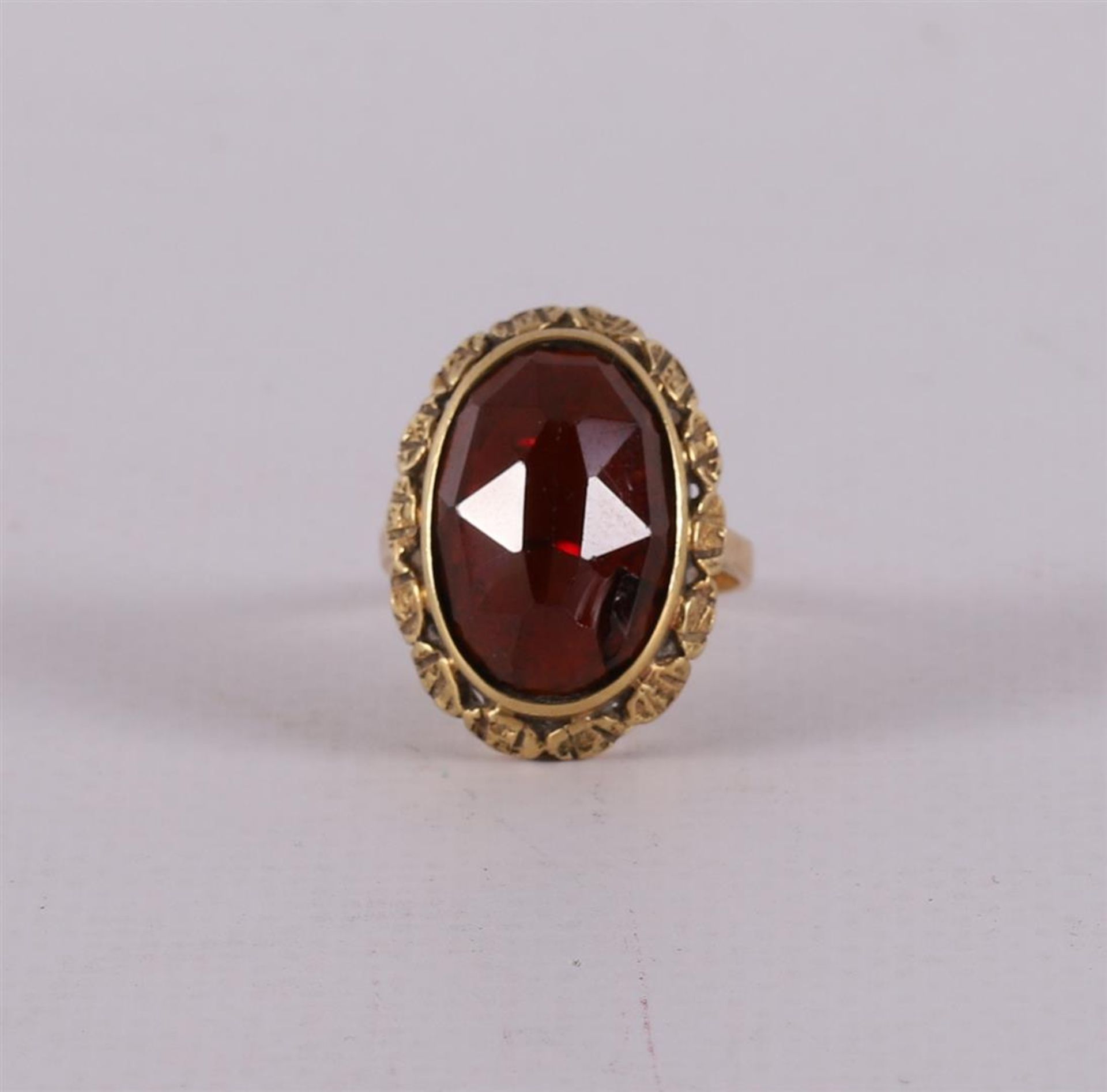 A 14 kt yellow gold ring, set with a faceted oval garnet.