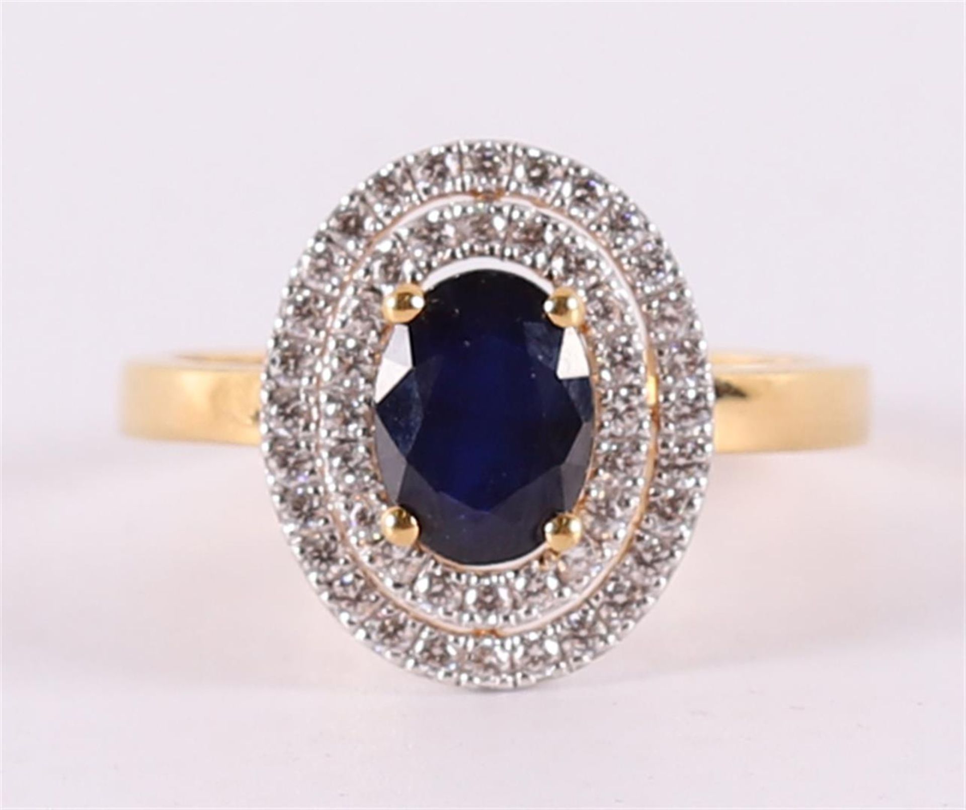 A 9 kt BWG ring with facet cut blue sapphire, flanked by zirconias