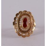 A 14 kt yellow gold ring, set with a faceted oval garnet.