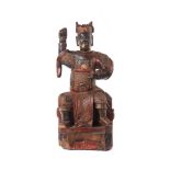 A carved wooden figure of a seated warrior