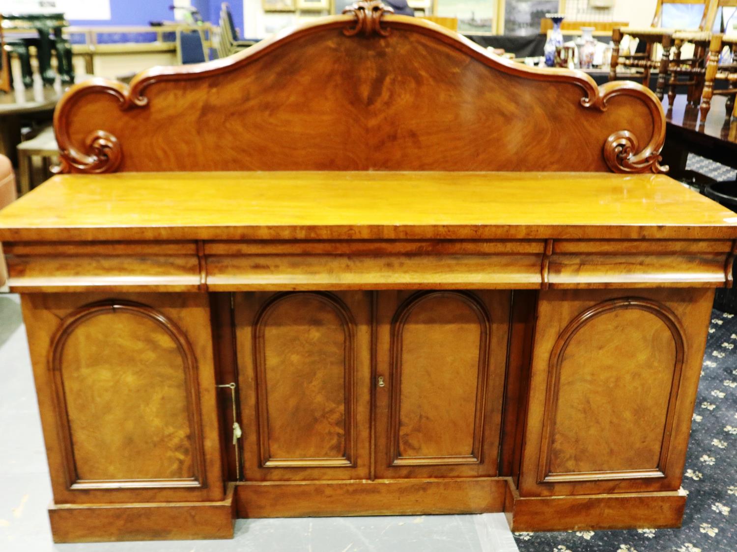 A 19th century flame mahogany buffet, having three drawers above four locking cupboards and carved