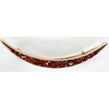 Victorian 9ct rose gold crescent brooch, set with thirteen graduated red stones, L: 50 mm, 2.9g. P&P