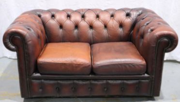 A 20th century ox blood red leather Chesterfield style two seat sofa. Not available for in-house P&P