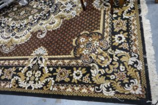 A 20th century floor rug, fringed and with floral designs against a black ground. Not available