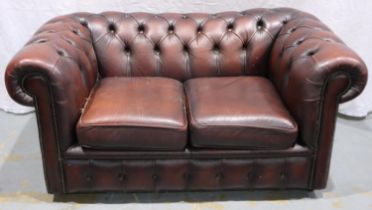 A 20th century ox blood red leather Chesterfield style two seat sofa. Not available for in-house P&P