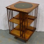 A 20th century walnut revolving bookcase, inlaid and with tooled leather inset top, damage to one