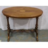 An Edwardian inlaid walnut oval lamp table, with quartered veneer, raised on carved and turned