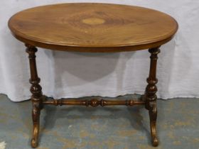 An Edwardian inlaid walnut oval lamp table, with quartered veneer, raised on carved and turned