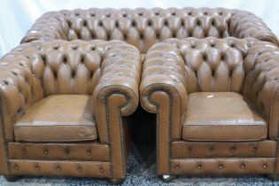 A 20th century tan leather Chesterfield lounge suite comprising a three seat sofa and two armchairs.