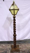 Oak lamp with turned stem and yellow glass shade with brass female motif mounts, H: 180 cm. Not