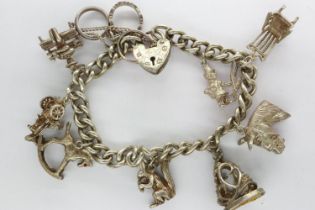 Hallmarked silver charm bracelet with padlock clasp, safety chain and nine charms, L: 18 cm, 49g. UK