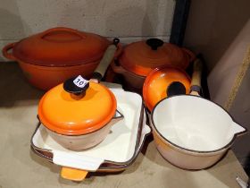 Three pans, stew pot and a casserole dish by Le Creuset, all in orange. Not available for in-house