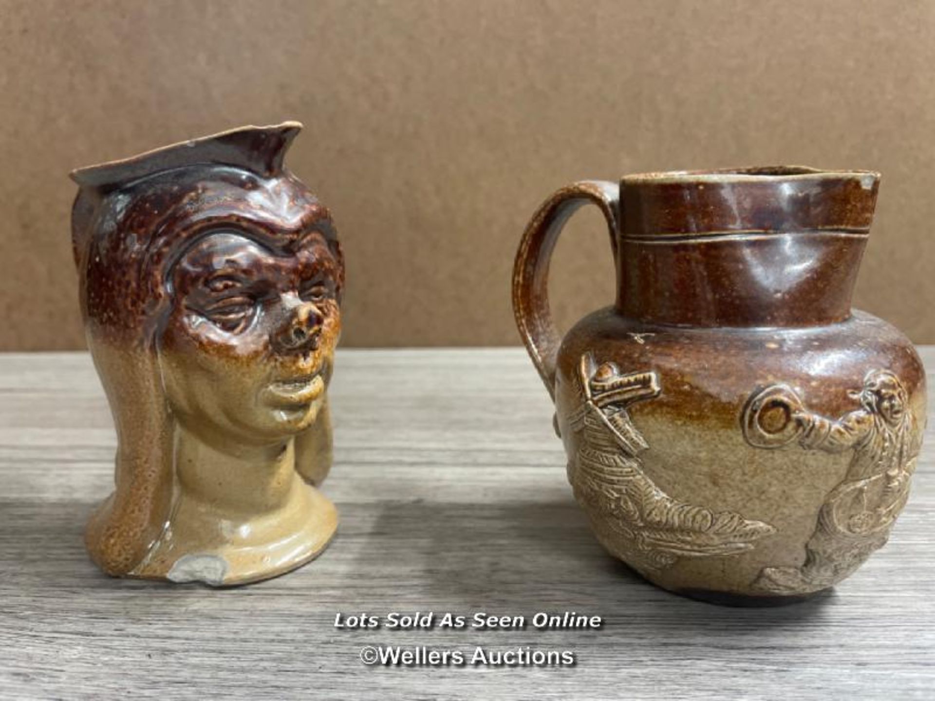 TWO STONEWARE JUGS, ONE MOULDED AS A PIG-NOSED WOMAN