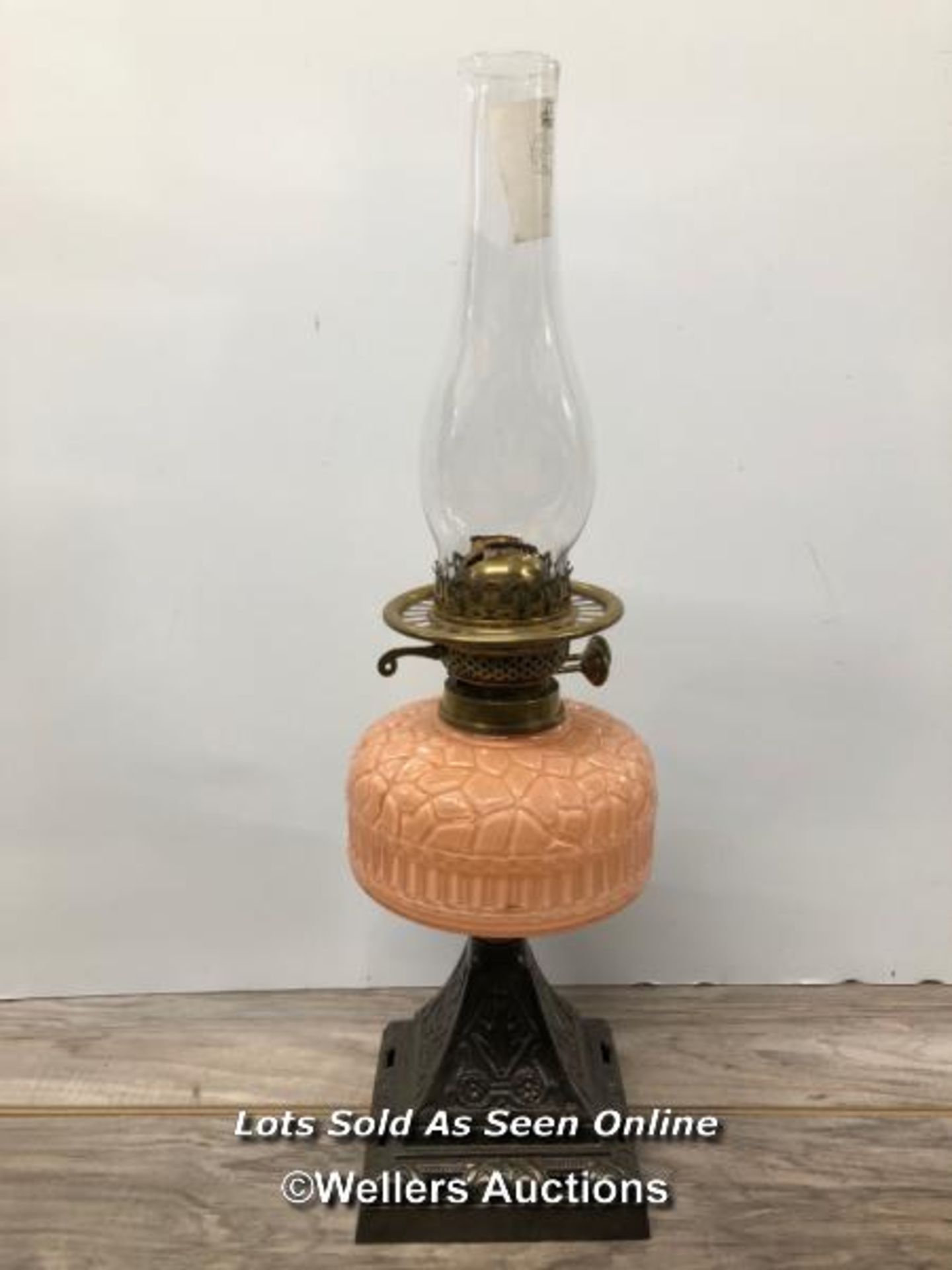 *OIL LAMP WITH PINK GLASS RESERVOIR AND CAST IRON BASE