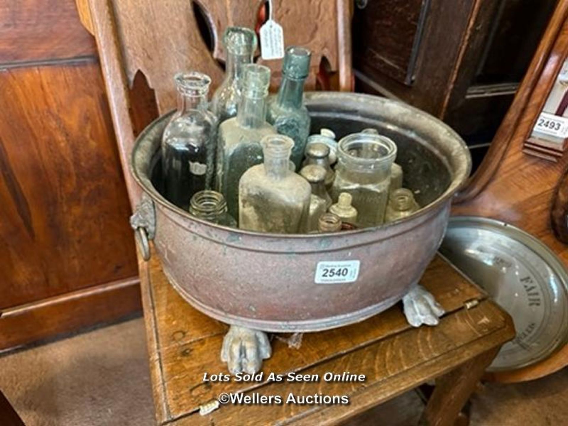 *APPROX 25 OLD GLASS BOTTLES IN A COPPER JARDINIERE / LOCATED AT VICTORIA ANTIQUES, WADEBRIDGE, PL27