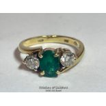 AN EMERALD AND DIAMOND THREE STONE RING IN CROSSOVER STYLE. EMERALD MEASURES APPROX 6.9 X 5.1 X 3.