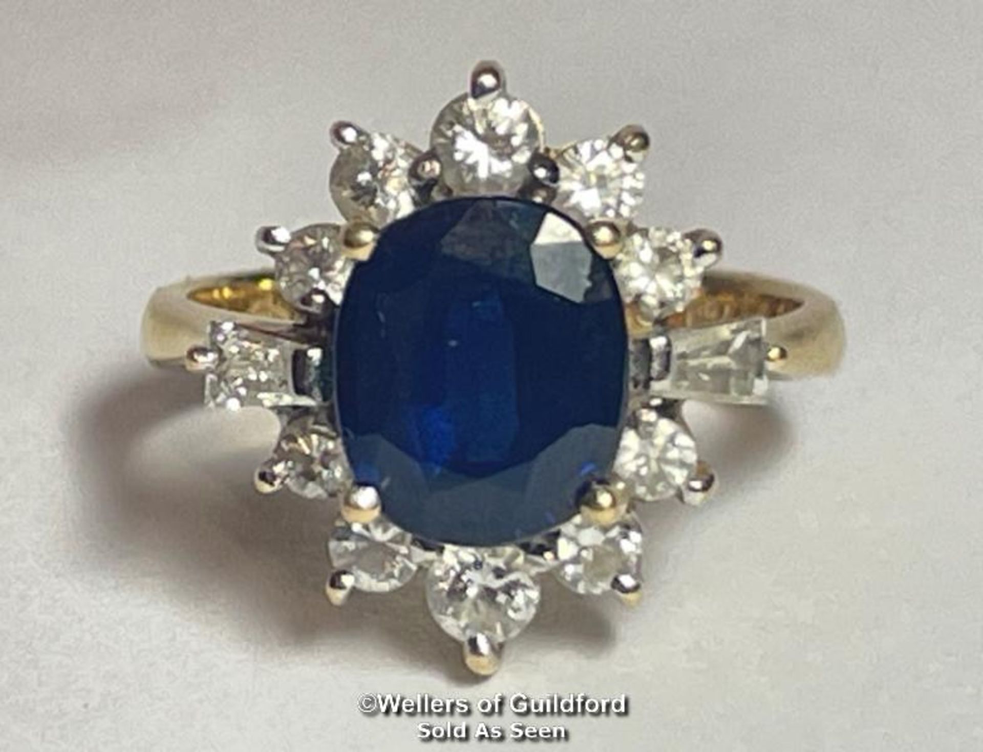 A SAPHIRE AND DIAMOND OVAL CLUSTER RING, THE SAPHIRE MEASURES APPROX 8.4 X 7.1 X 4.1MM, ESTIMATED