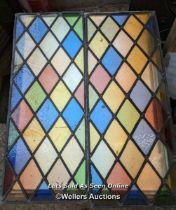 A pair of stained glass panels with diamond harlequin designed leaded glass. Some cracks and breaks.