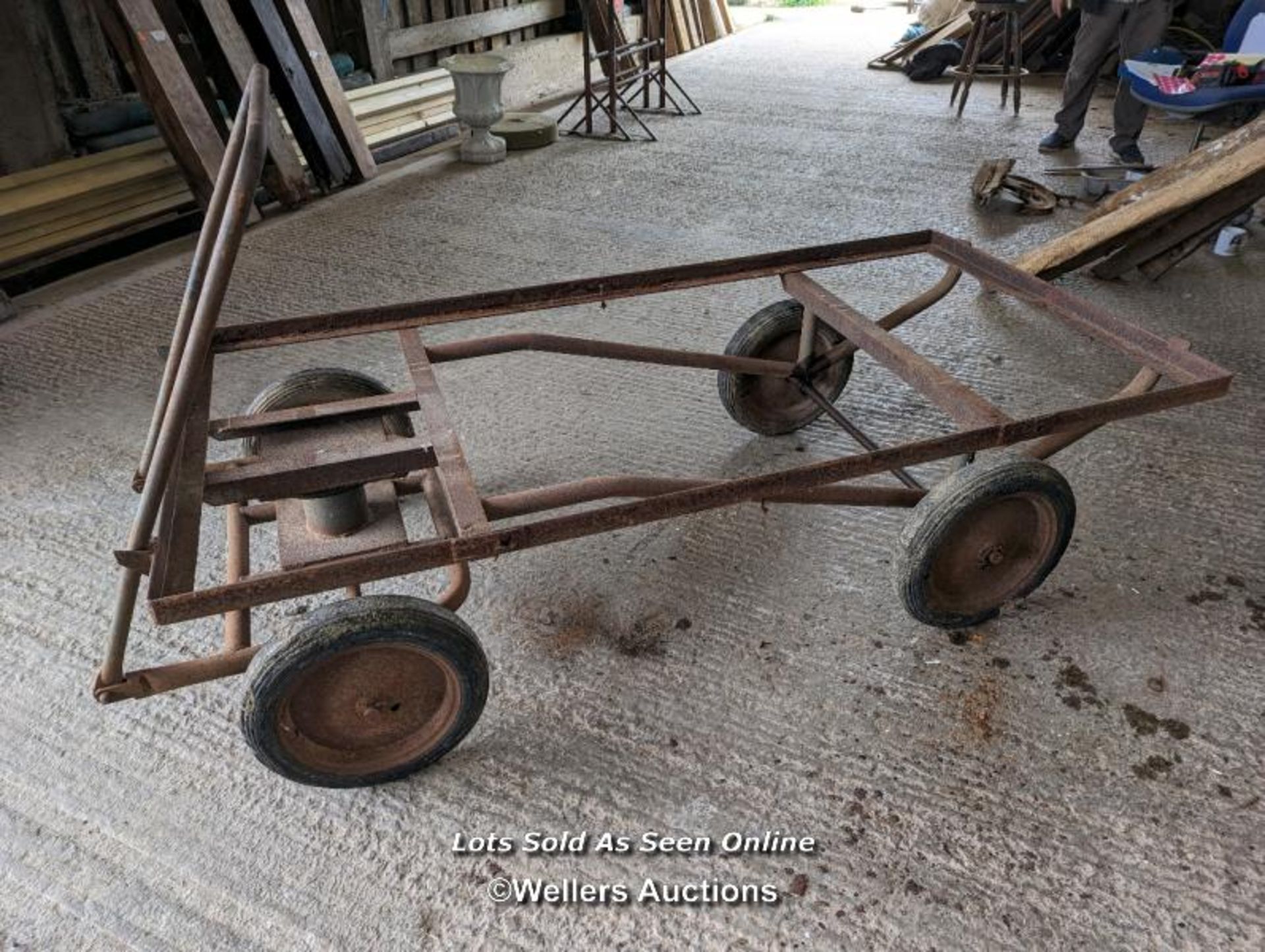 Vintage trolley on wheels with solid rubber tyres. All wheels turning, front axle. Angle iron