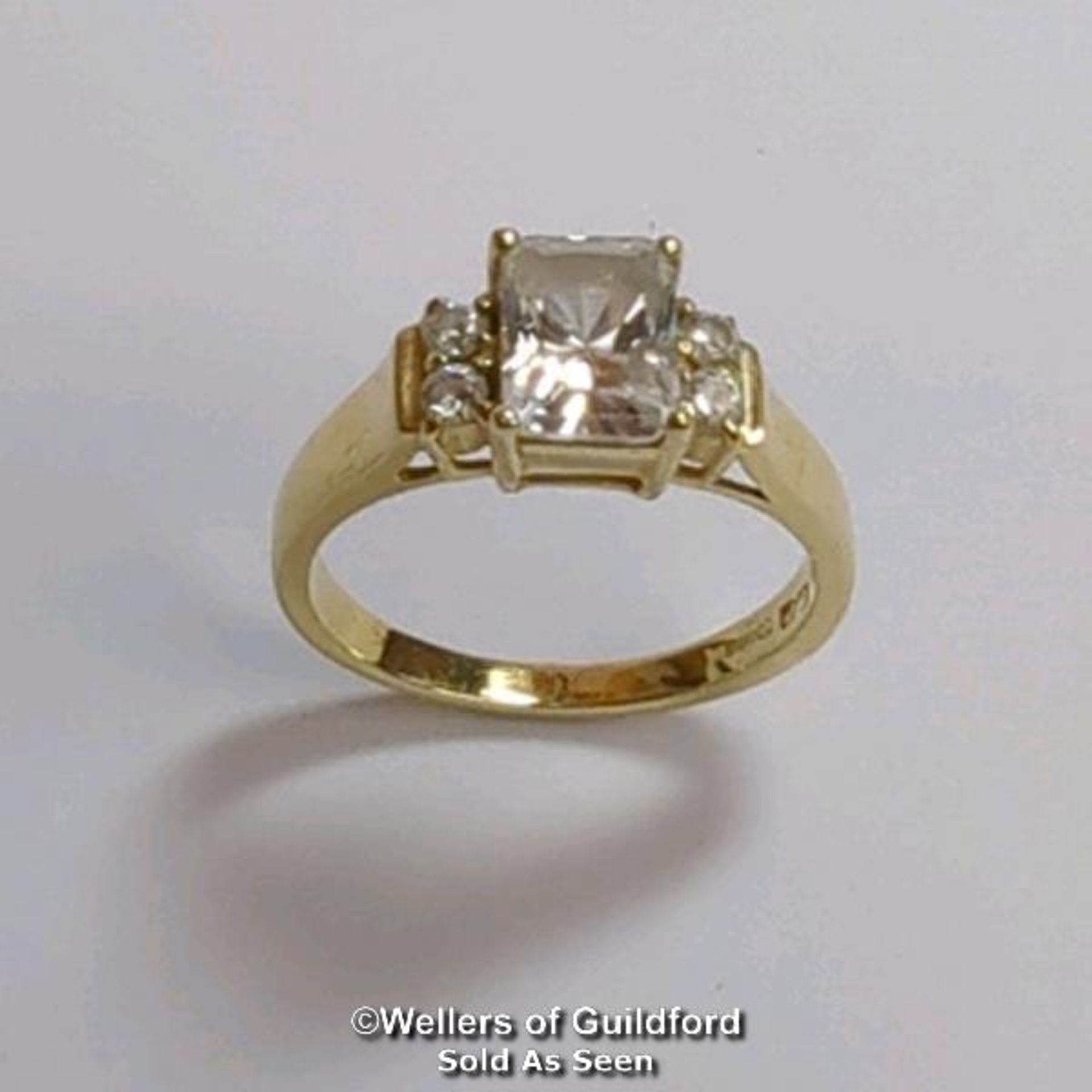 A cubic zirconia dress ring in hallmarked 14ct gold. The emerald cut centre stone measures 7mm x 5.