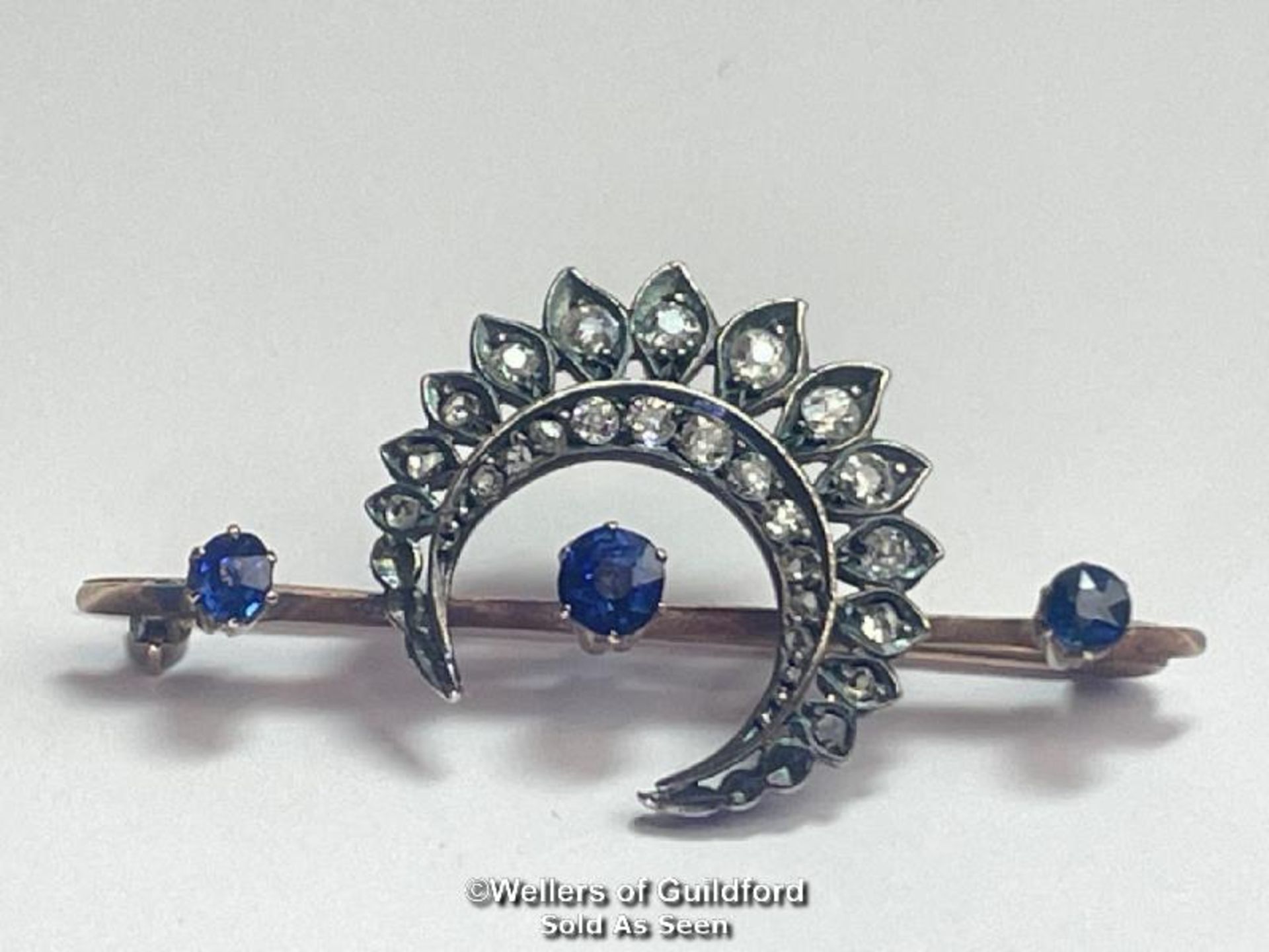 Late Victorian diamond and sapphire cresent bar brooch. Three round old cut sapphires estimated