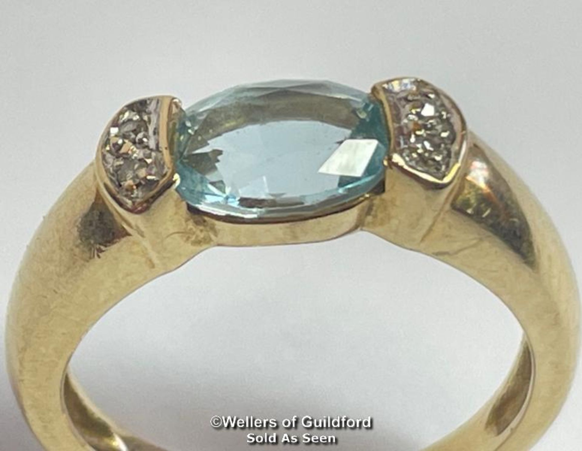 Oval blue topaz (untested) ring in yellow metal stamped 585, with diamond accents. Ring size K1/2,