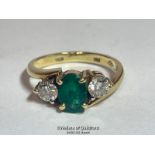 An emerald and diamond three stone ring in crossover style. Emerald measures approx 6.9 x 5.1 x 3.