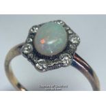 Opal and diamond cluster ring. An oval opal surrounded by a border of old cut diamonds forming a
