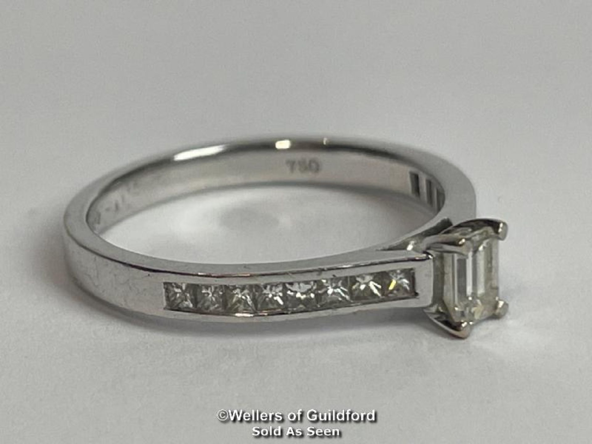 An emerald cut diamond solitaire ring with diamond shoulders, in hallmarked 18ct white gold. - Image 4 of 6