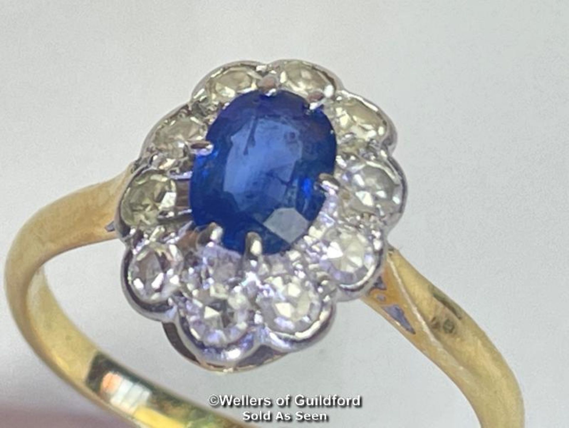Sapphire and diamond cluster ring. An oval sapphire estimated weight 0.55ct surrounded by ten single