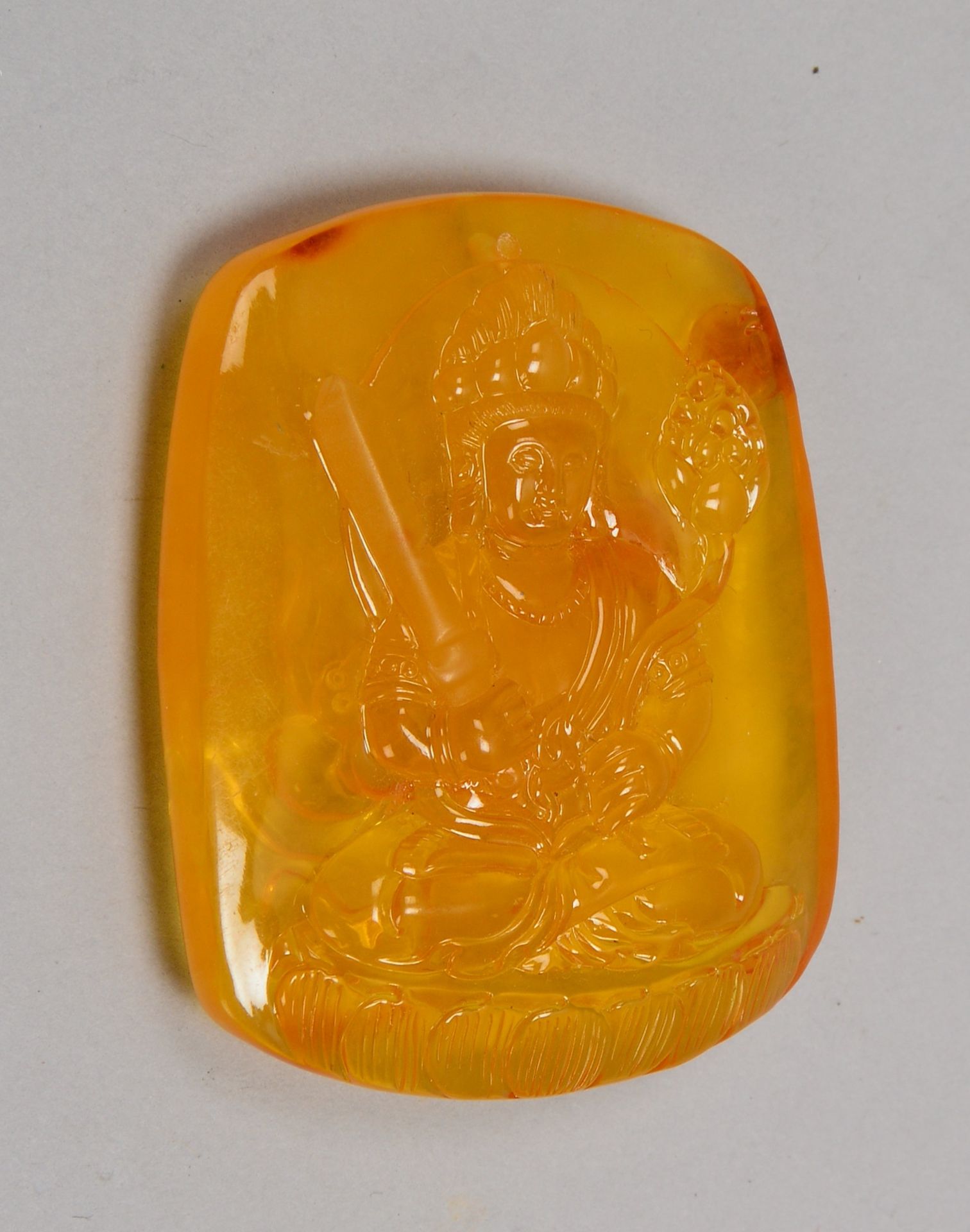 Bernsteinschnitzerei mit Reliefdekor, 'Sitzender Buddha'; Maße 5,7 x 4,7 x 1,3 cm