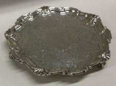 A circular silver waiter with floral decoration. S