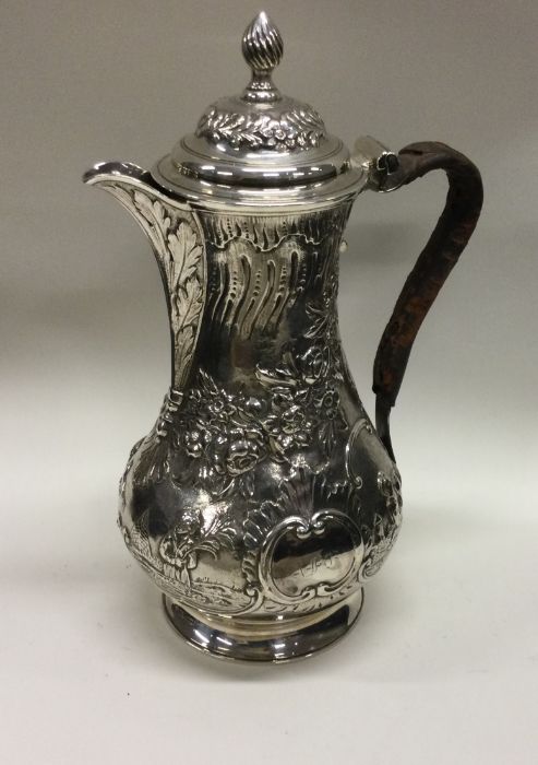A heavy chased 18th Century Georgian silver jug of Chinoiserie design. London 1766. By Thomas and
