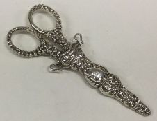 A pair of embossed silver scissors contained withi