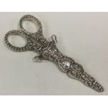 A pair of embossed silver scissors contained withi