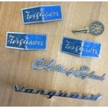 A Vanguard car badge together with other car badges.