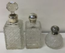 A group of three cut glass and silver mounted scent bottles.