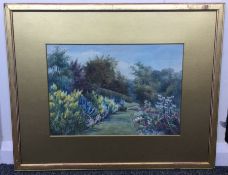 A gilt framed and glazed watercolour depicting cottage garden flowers and trees.