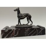 A silver figure of a dog on stand.