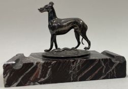 A silver figure of a dog on stand.