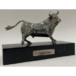 A silver figure of a bull on stand.